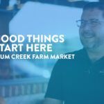 A smiling bearded man with glasses and a company shirt that says "Plum Creek" with text overlaid that reads "Good things start here. Plum Creek Farm Market".