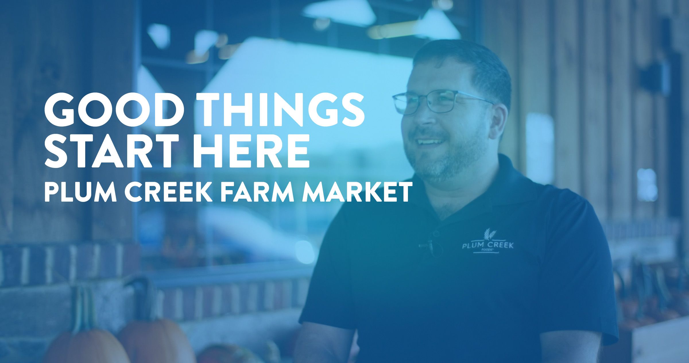 A smiling bearded man with glasses and a company shirt that says "Plum Creek" with text overlaid that reads "Good things start here. Plum Creek Farm Market".